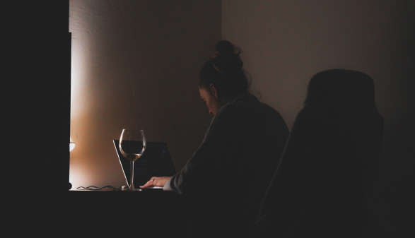 Frau im Homeoffice vor einem Computer mit einem Glas Wein in dunkler Atmosphäre © Czapp Árpád, Pexels