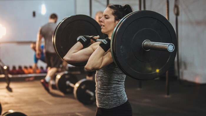 Eine Frau hebt eine Langhantel im Fitnessstudio und zeigt ihre Kraft und Entschlossenheit beim Training.  