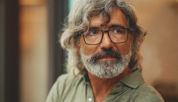Portr&auml;t eines &auml;lteren Mannes mit graumeliertem Haar, Brille und Bart, der mit nachdenklichem Blick zur Seite schaut.