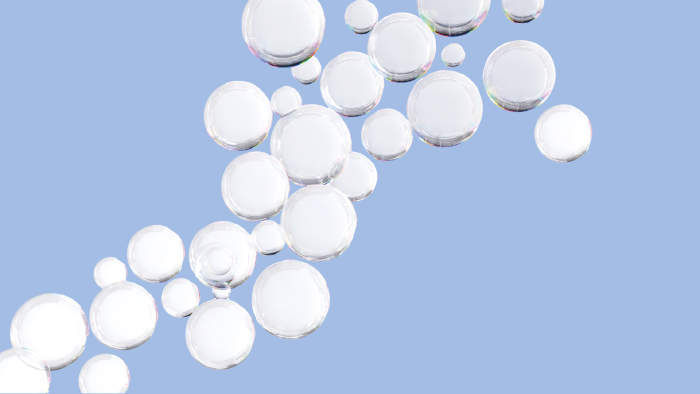 Mehrere durchsichtige Seifenblasen in unterschiedlichen Gr&ouml;&szlig;en schweben diagonal &uuml;ber einen hellblauen Hintergrund.