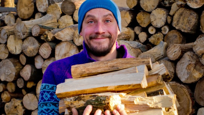 Ein Mann der Brennholz trägt © leo_nik, Adobe Stock