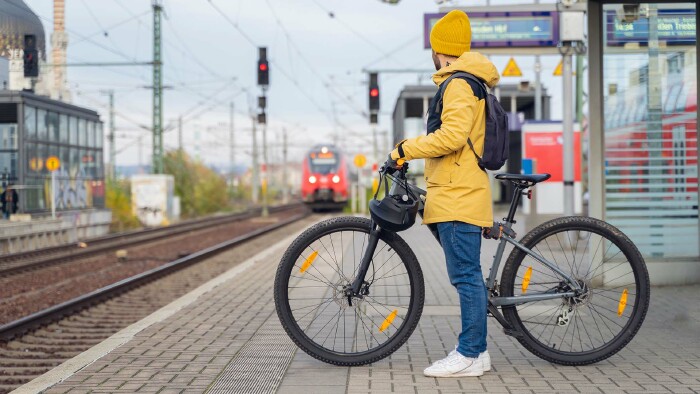 Ein Mann steht mit seinem Fahrrad an einem Bahnsteig.