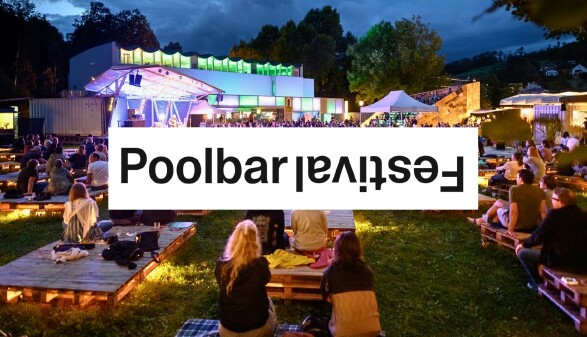 Au&szlig;enaufnahme des poolbar Festivals im Reichenfeld. Menschen sitzen gem&uuml;tlich auf B&auml;nken und Liegen. In der Mitte der Schriftzug: Poolbar Festival