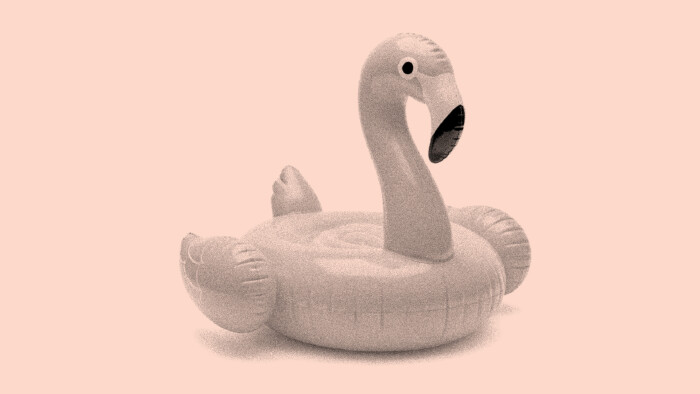 Aufblasbarer Flamingo-Schwimmreifen vor einfarbigem, pastellrosa Hintergrund, im Retro-Look mit leichter Körnung dargestellt.