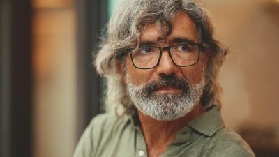 Portr&auml;t eines &auml;lteren Mannes mit graumeliertem Haar, Brille und Bart, der mit nachdenklichem Blick zur Seite schaut.