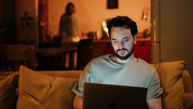 Mann sitzt abends zu Hause am Laptop und wird online Opfer eines Recovery-Scams &ndash; Symbolbild f&uuml;r Internetbetrug und digitale Finanzfallen