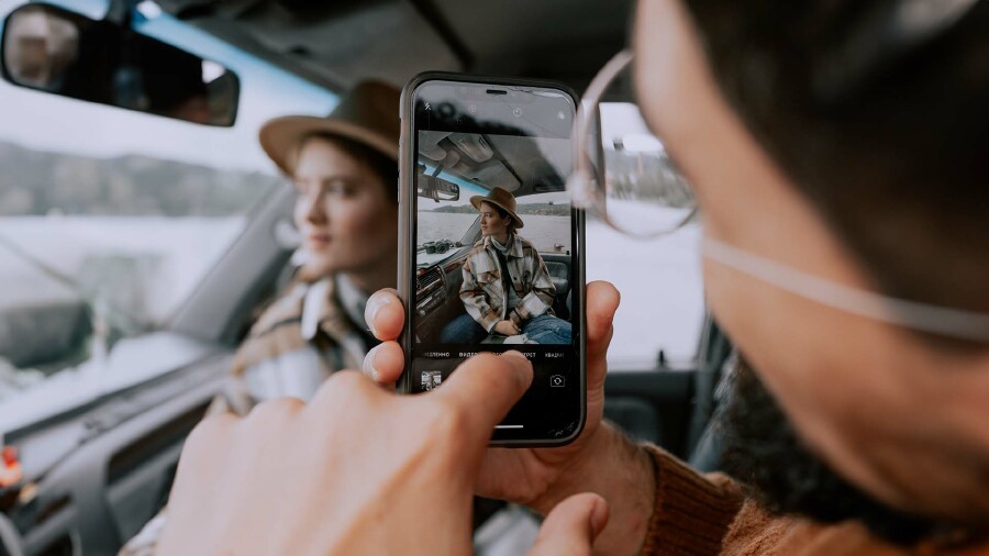 Ein Mann fotografiert eine Frau mit einem Handy.
