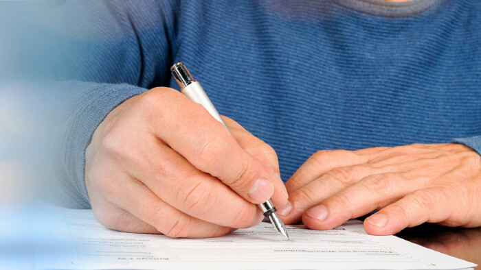 © jozsitoeroe, Adobe Stock Mann unterschreibt Antrag