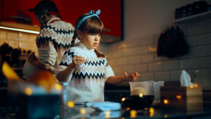 Ein Mächen steht in der Küche und bäckt Weihnachtskekse.