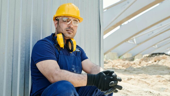 Ein Bauarbeiter sitzt auf einer Baustelle.