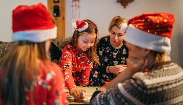 Ein Mädchen spielt mit seiner Familie ein Brettspiel.