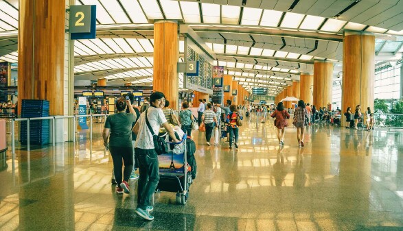 Menschen am Flughafen mit Gepäck – sicher Flüge buchen und Flug-Abzocke vermeiden
