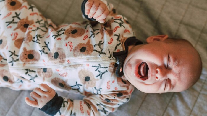 Ein weinendes Baby liegt auf einem Bett und zeigt seine Traurigkeit in einem emotionalen Moment.