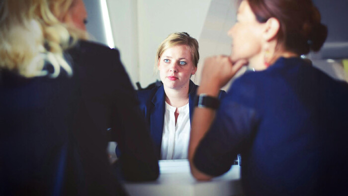 Kein gutes Gefühl im Bewerbungsgespräch? Es kann eine gute Idee sein, auf deinen Bauch zu hören. © Tim Gouw, Pexels Eine verunsichert und nervös aussehende blonde Frau sitzt bei einem Bewerbungsgespräch zwei Frauen gegenüber, die miteinander reden.