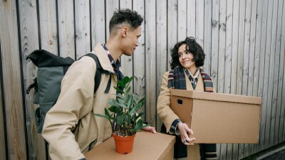 Ein Mann und eine Frau tragen Umzugskisten in ein Haus.