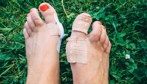 Zwei verletzte Füße mit Blasen und Pflastern auf grünem Rasen – symbolisches Bild für die Probezeit im Job: Ein Arbeitsplatz muss genauso gut passen wie Schuhe, sonst entstehen schmerzhafte Druckstellen.