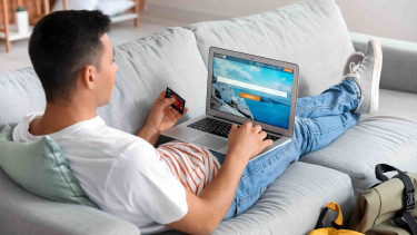 Mann auf der Couch bucht einen Flug online © Pixel-Shot, stock.adobe.com
