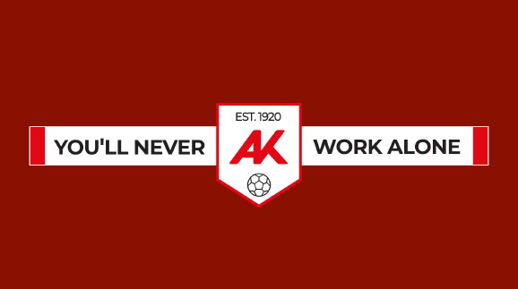 Grafik auf dunkelrotem Hintergrund: Ein wei&szlig;er Fanschal mit der Aufschrift &sbquo;YOU&rsquo;LL NEVER WORK ALONE&lsquo;. In der Mitte wird der Schal von einem wei&szlig;en Wappen unterbrochen, das das rote AK-Logo, das Gr&uuml;ndungsjahr &sbquo;EST. 1920&lsquo; und ein Fu&szlig;ball-Icon zeigt.