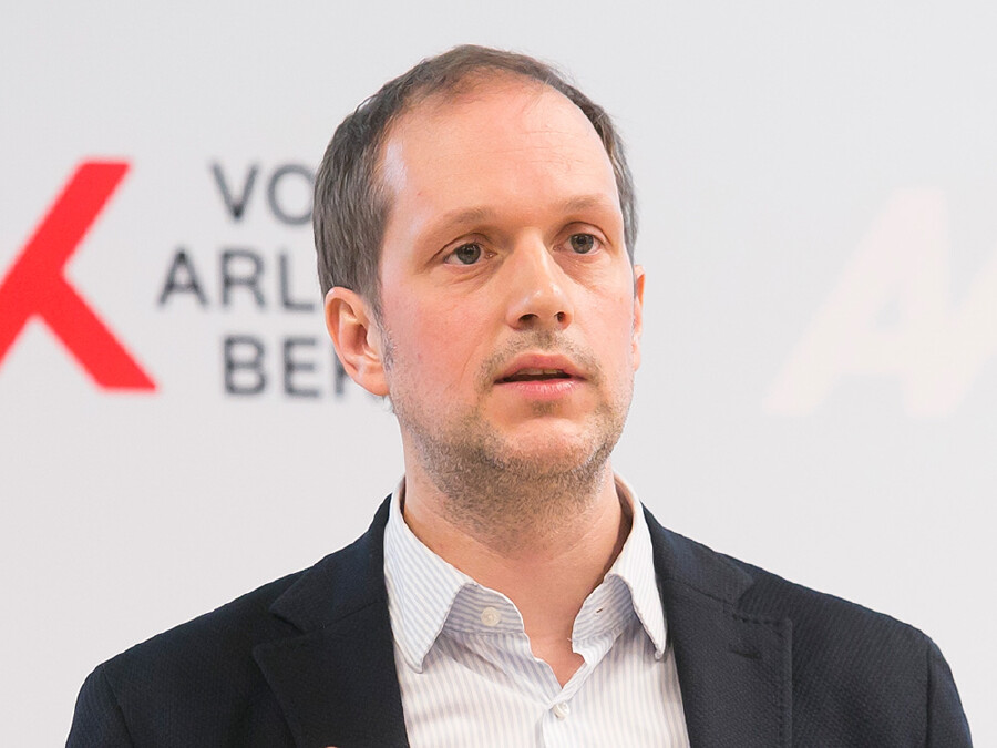 Portr&auml;t von Michael Klien, &Ouml;konom beim WIFO, bei der Pressekonferenz der Arbeiterkammer Vorarlberg. Im Hintergrund ist das Logo der AK Vorarlberg zu sehen.