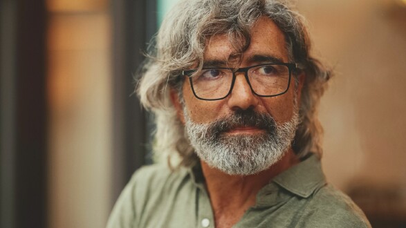 Portr&auml;t eines &auml;lteren Mannes mit graumeliertem Haar, Brille und Bart, der mit nachdenklichem Blick zur Seite schaut.