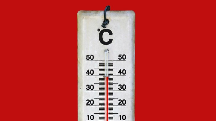 Ein verwittertes, wei&szlig;es Au&szlig;enthermometer mit einer schwarzen Metallaufh&auml;ngung h&auml;ngt vor einem einfarbigen roten Hintergrund. Die Skala zeigt Grad Celsius (&deg;C) an, mit schwarzen Ziffern von 10 bis 50. Die rote Fl&uuml;ssigkeitss&auml;ule im Glasr&ouml;hrchen steht mittig und reicht knapp an den 30-Grad-Markenstrich heran. Die Zahlen 10, 20, 30, 40 und 50 sind sowohl links als auch rechts von der S&auml;ule ablesbar.