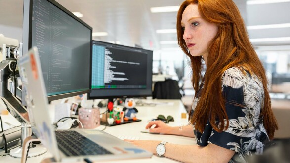 Eine Frau sitzt am Schreibtisch und arbeitet am Computer.