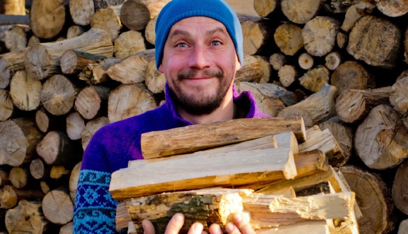 Ein Mann der Brennholz trägt © leo_nik, Adobe Stock