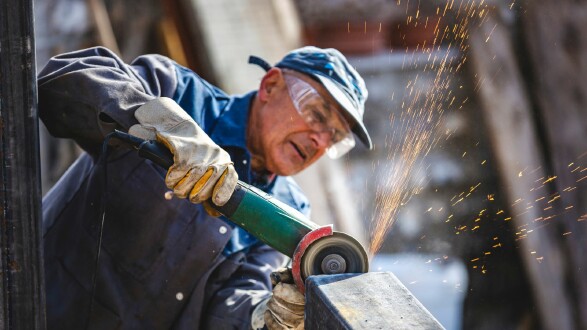 Älterer Mann auf einer Baustelle mit einem Winkelschleifer © Canva