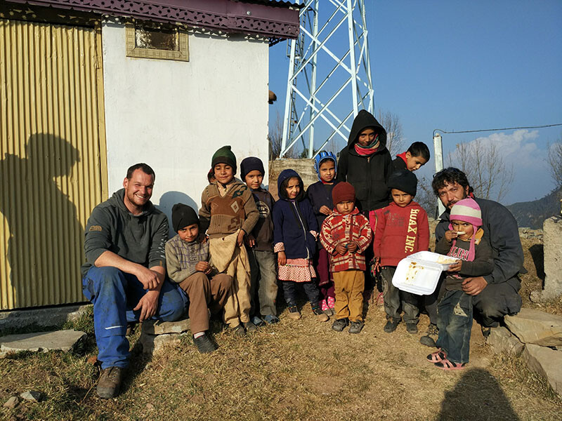 Elmar Röck nimmt sich bei jedem Einsatz die Zeit, Land und Leute kennenzulernen – wie hier in Pakistan. © Elmar Röck Elmar Röck und eine Gruppe von zehn kleinen Kindern sitzen zusammen im Kreis und lachen in die Kamera.