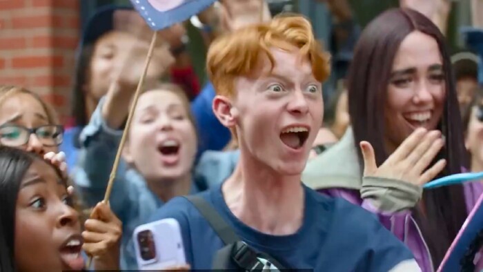 Screenshot aus dem Amazon-Werbespot: Ein Mann mit überzeichneter Mimik und glattem Gesichtsausdruck feiert sich selbst, umgeben von weiteren jubelnden Personen