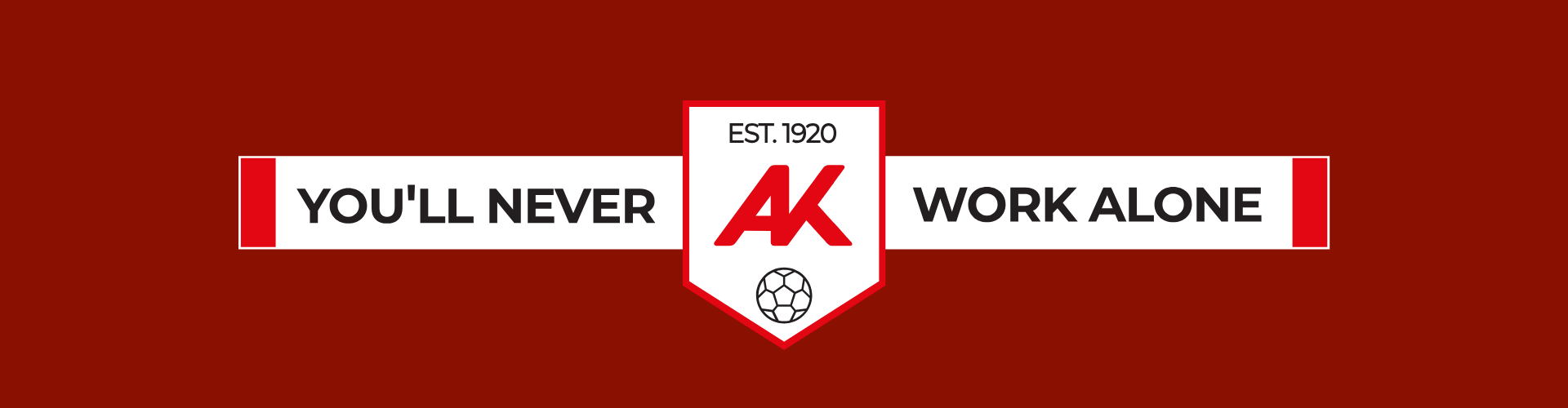 Werbebanner im Querformat auf dunkelrotem Hintergrund. In der Mitte befindet sich ein gro&szlig;es, wei&szlig;es Wappen-Logo der Arbeiterkammer (AK) mit der Aufschrift &bdquo;EST. 1920&ldquo; und einer Fu&szlig;ball-Grafik im unteren Teil. Links und rechts vom Wappen erstreckt sich ein wei&szlig;er Balken im Schal-Design mit roten Enden, auf dem in schwarzen Gro&szlig;buchstaben der Slogan &bdquo;YOU'LL NEVER WORK ALONE&ldquo; aufgeteilt ist.