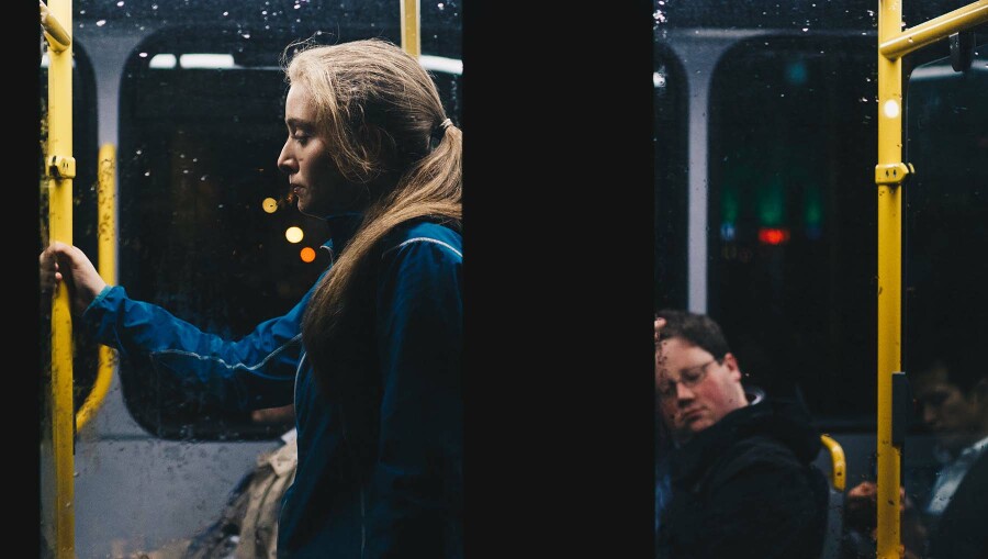 Eine Frau steht mit anderen Fahrgästen in einem Bus.