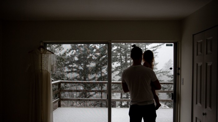 Vater mit Kind auf dem Arm blickt aus dem Fenster, draußen schneit es.