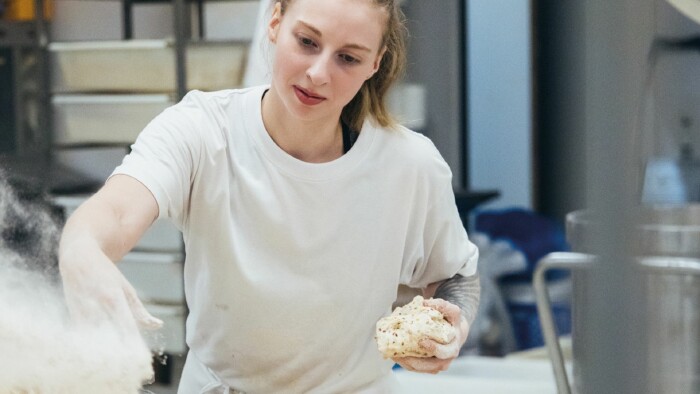 Bäckerin bei der nächtlichen Teigzubereitung in professioneller Backstube – engagierte Handarbeit, während andere schlafen, für frisches Brot am Morgen.