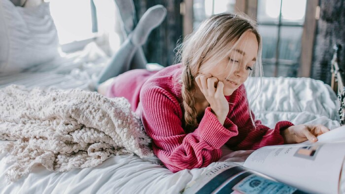 Anzeigen in Zeitschriften gehören zu den ältesten Werbeformen. © Leah Newhouse, Pexels Eine Frau liegt auf einem Bett und blättert in einer Zeitschrift.