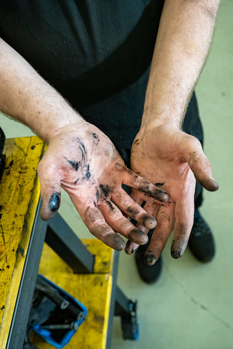 Werner Metzler h&auml;lt seine von Motor&ouml;l und Schmierfett verschmutzten Handfl&auml;chen in die Kamera &ndash; sichtbares Zeichen handwerklicher Arbeit in der Oldtimer-Werkstatt.