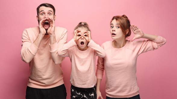 Überraschte junge Familie, die auf rosa Hintergrund in die Kamera blickt © master1305, Adobe Stock