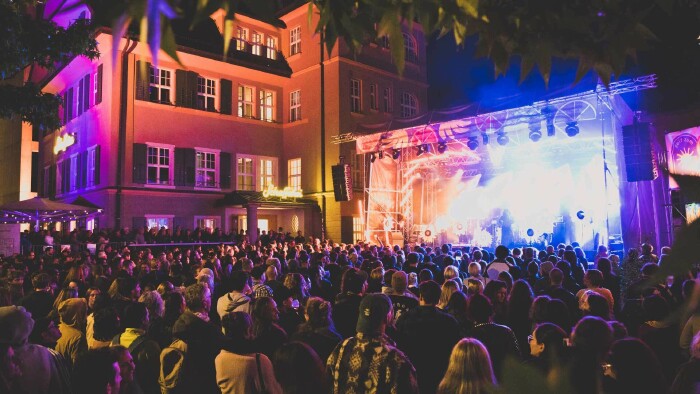 Das Schaffarei Festival 2025 stellte einen neuen Besucherrekord auf. © Patricia Keckeis Ein große Menschenmenge steht vor einer beleuchteten Bühne, auf der eine Band gerade ein Konzert gibt.