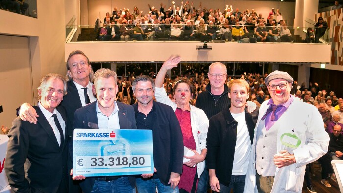 Die Kabarettisten Lins, Kräutler, Trenkwalder und Linder gemeinsam mit Vertretern der CliniClowns und des Vereins Sonnenblume sowie mit AK Präsident Bernhard Heinzle gemeinsam auf der Bühne bei der Scheckübergabe.