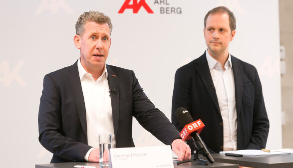 Pressekonferenz der Arbeiterkammer Vorarlberg: AK-Pr&auml;sident Bernhard Heinzle (links) spricht an einem Tisch mit einem ORF-Mikrofon, neben ihm steht Michael Klien vom WIFO (rechts). Im Hintergrund ist das Logo der AK Vorarlberg zu sehen.