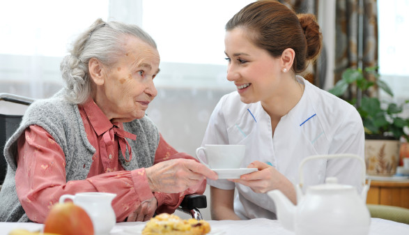 Pflegerin mit älterer Dame beim Tee