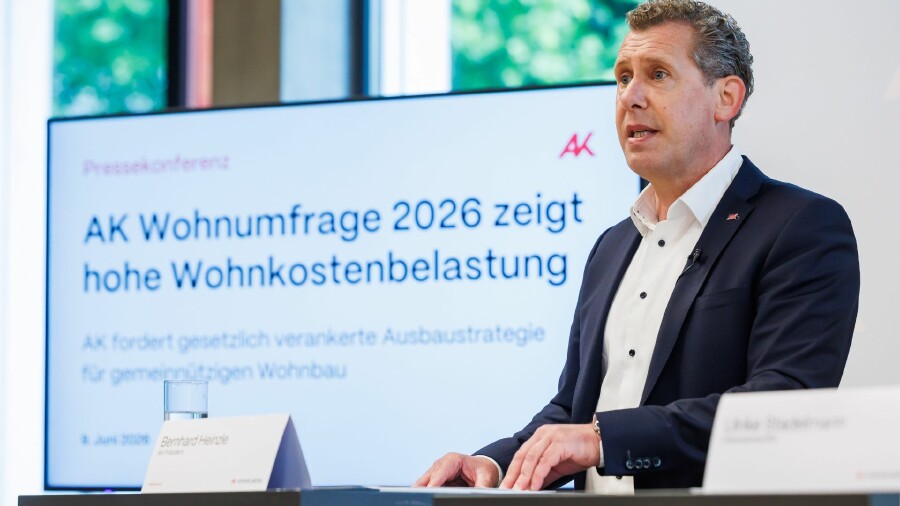 AK Pr&auml;sident Bernhard Heinzle bei einer Pressekonferenz. Im Hintergrund ein Bildschirm mit einer Powerpoint-Folie, auf der steht: &bdquo;AK Wohnumfrage 2026 zeigt hohe Wohnkostenbelastung&ldquo;&ldquo;
