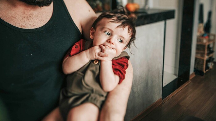 Ein Vater umarmt sein Baby, das sanft in seinen Armen liegt, und strahlt Zuneigung aus.