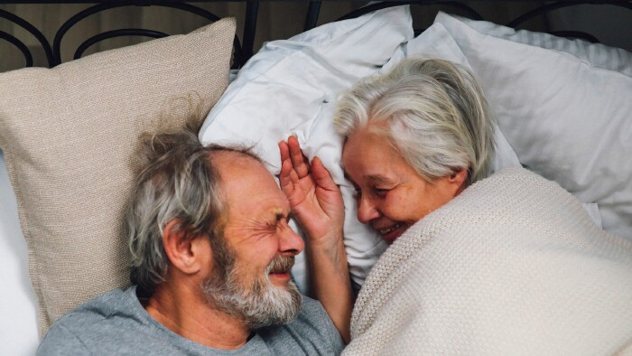 Ein älteres Paar liegt lachend im Bett