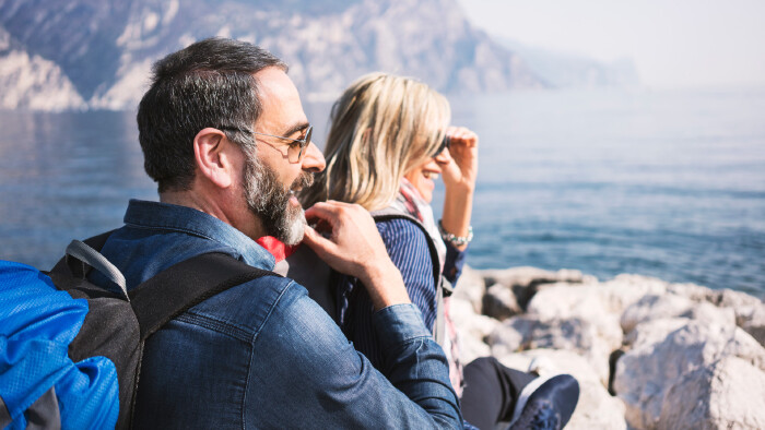 Ein Paar mit Sonnenbrillen sitzt am Ufer und schaut gemeinsam in die Ferne