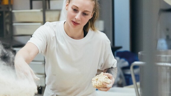 Bäckerin bei der nächtlichen Teigzubereitung in professioneller Backstube – engagierte Handarbeit, während andere schlafen, für frisches Brot am Morgen.