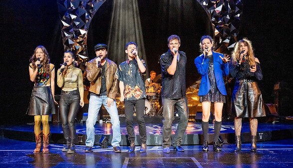 Männer und Frauen singend mit Mikrofon auf der Theaterbühne