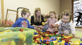 Drei Kinder und Betreuerin spielen mit Lego
