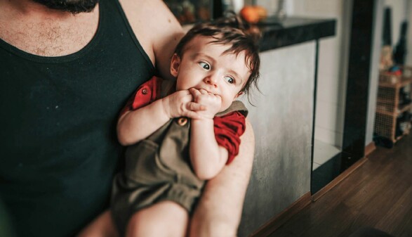 Ein Vater umarmt sein Baby, das sanft in seinen Armen liegt, und strahlt Zuneigung aus.