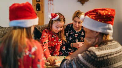 Ein Mädchen spielt mit seiner Familie ein Brettspiel.